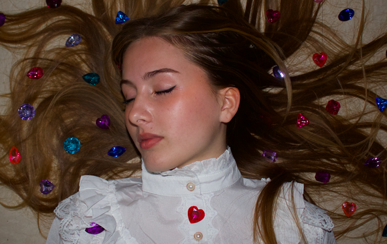 Huntington Beach High School student, Kat Hambrick, lays on the floor in a Victorian-era blouse with gems scattered about (Picture by: Izzy Vosper and Zachary Weisheit)