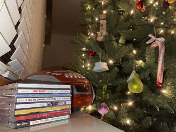 A list of Christmas music CDs, with a tree lit up behind it. 