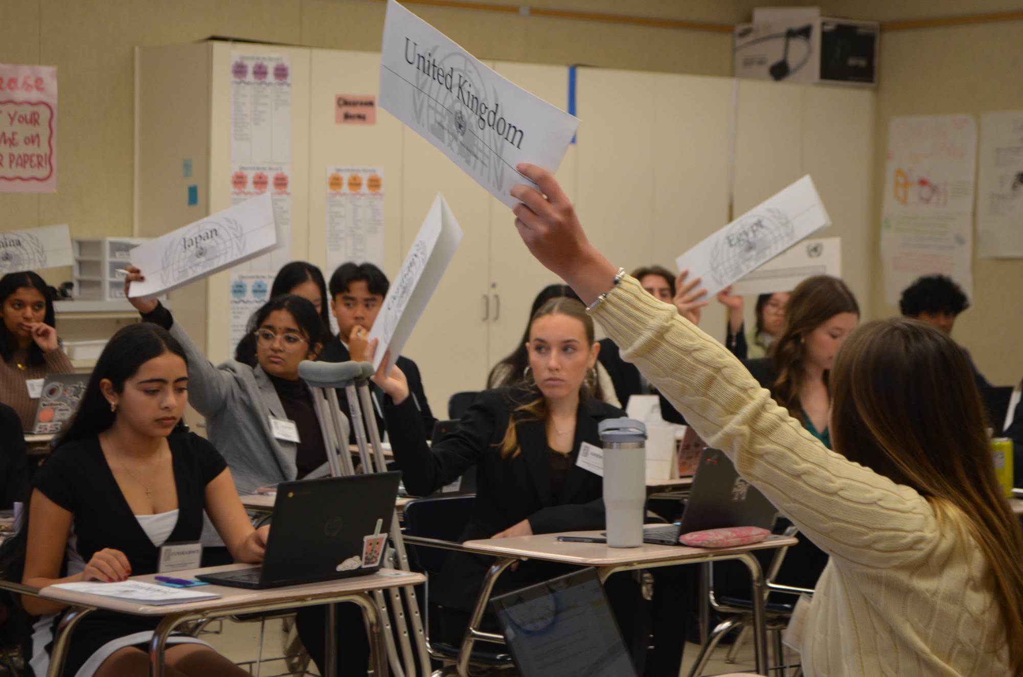 Delegates hold their placards while they await for the chairs to call on them.