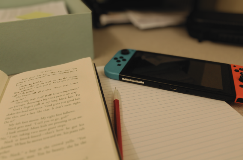 A distracting Nintendo Switch lies on a student's books as they study. 